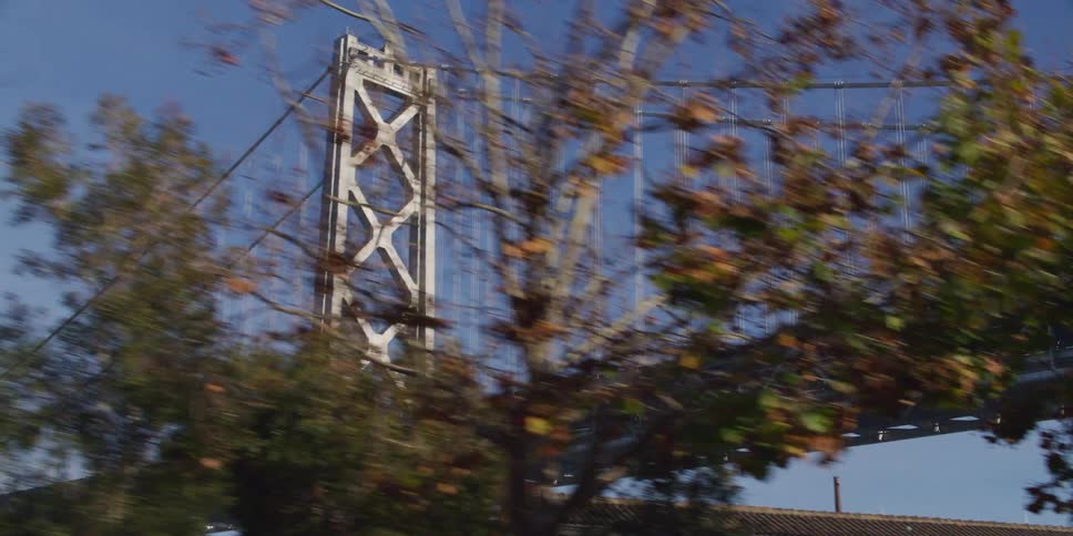Low rise buildings sit near suspension bridge under a clear sky