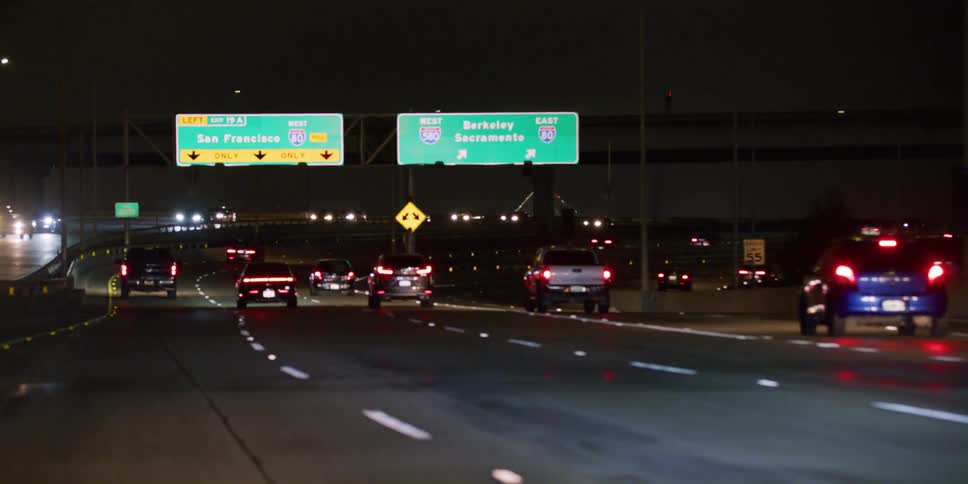 Cars are driving down an interstate at night