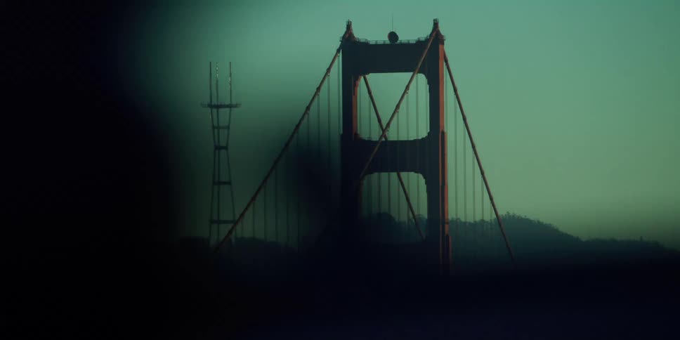 Cars are driving in a city near a bridge at dusk