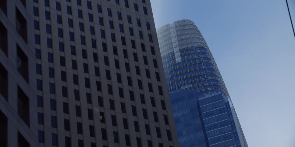 Power lines run over street bordered by skyscrapers under a blue sky