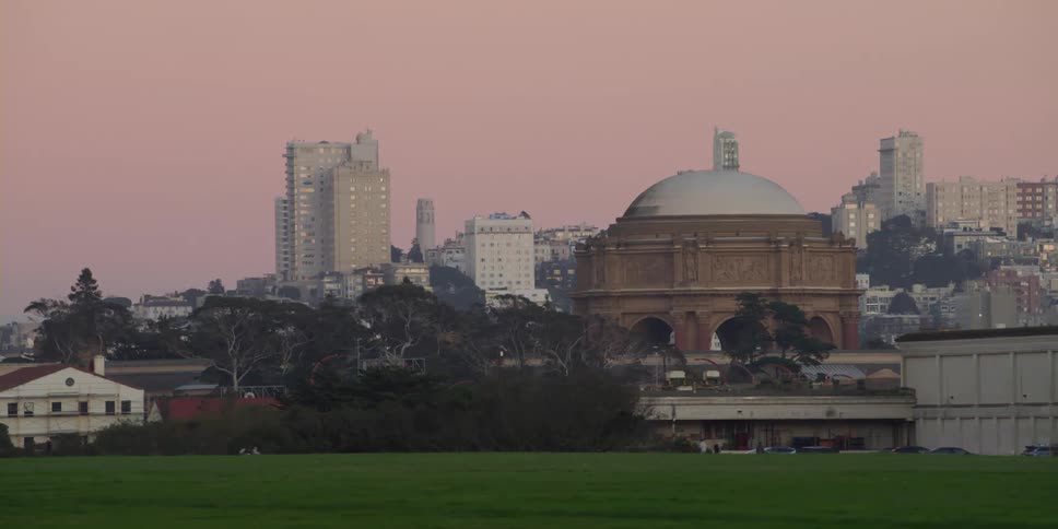 Man walks across field leading to city standing under red sky
