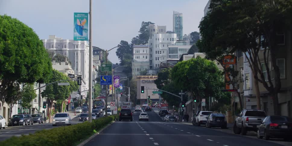 Cars are driving down the road through a city