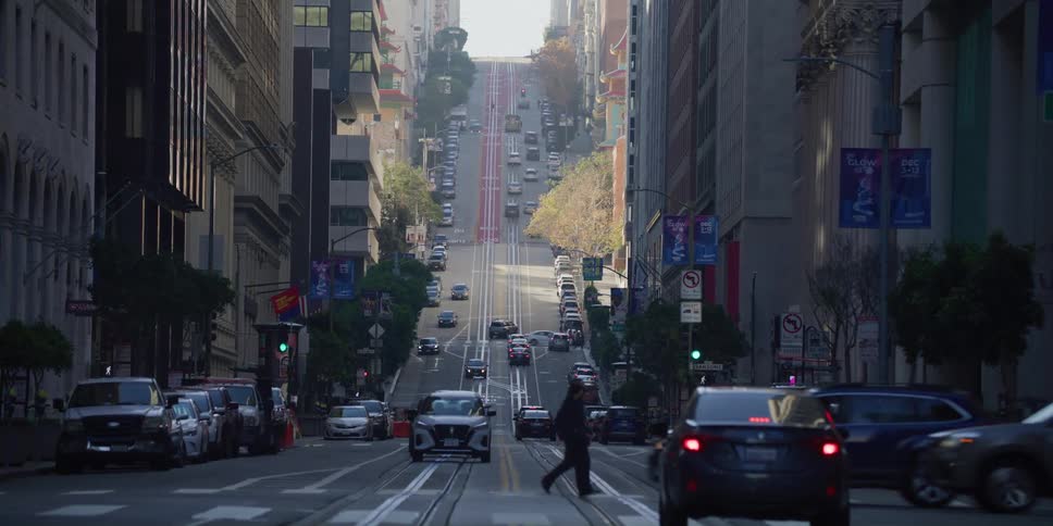 Pedestrians cross the street as cars travel through a downtown intersection