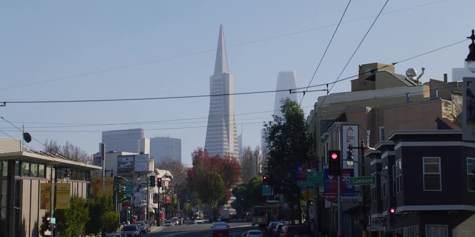 Cars are driving through a downtown city during the day