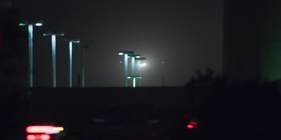 Driving near the lamp posts inside an industrial complex near the highway at night