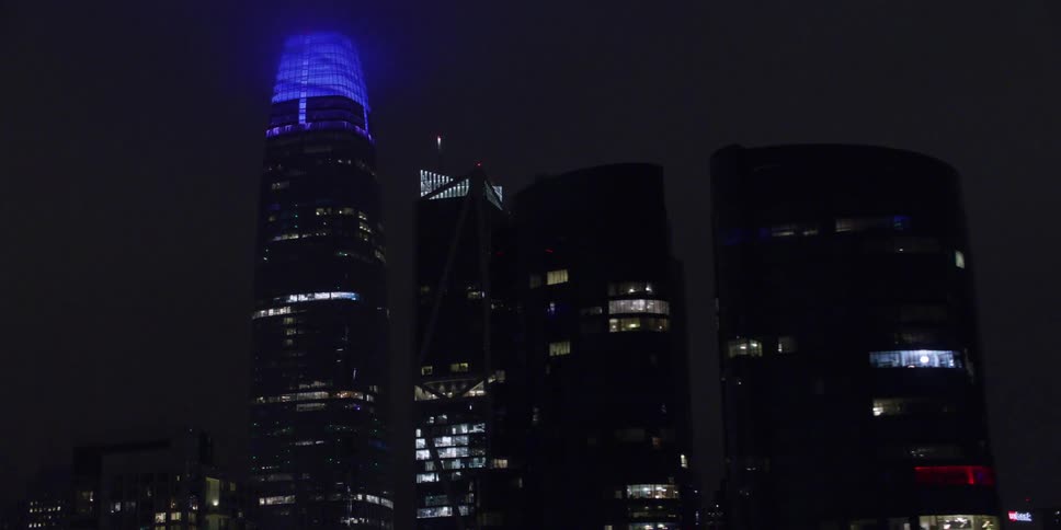 High rise buildings seen from moving car crossing bridge in the city at night