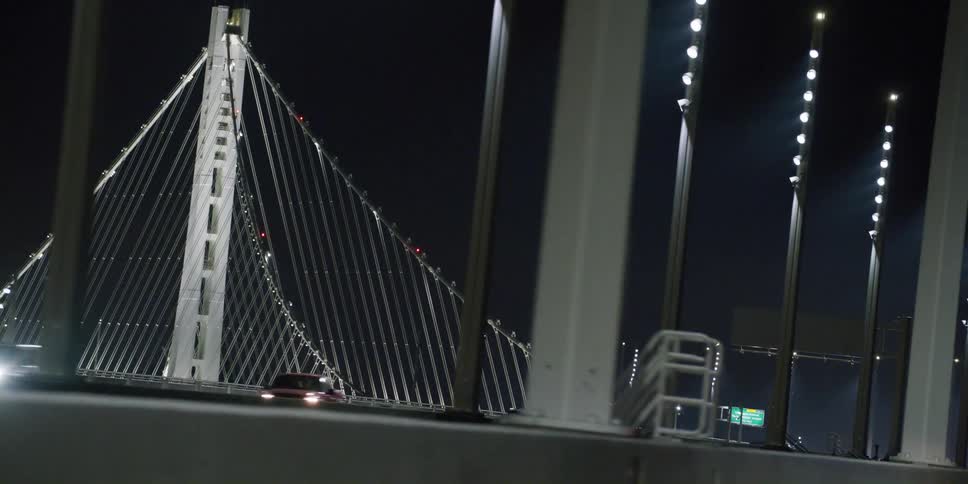 Road signs direct traffic along a bridge lit up at night