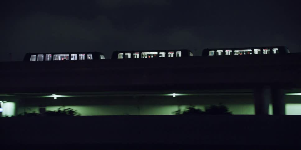 A commuter trains runs on a bridge parallel to a city street