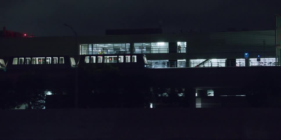 Train driving on an elevated track in the city close to buildings at night