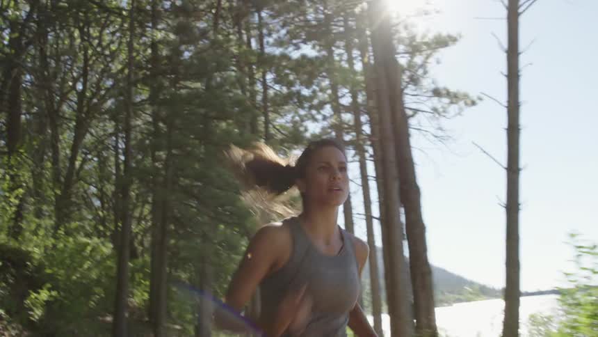 A woman is running near a lake on a sunny day
