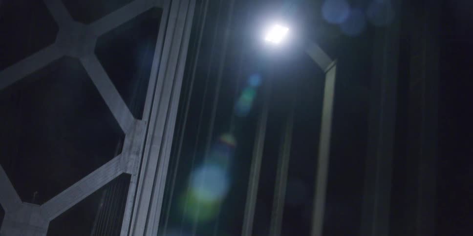 Traveling along a suspension bridge at night with a citys skyline in the foreground