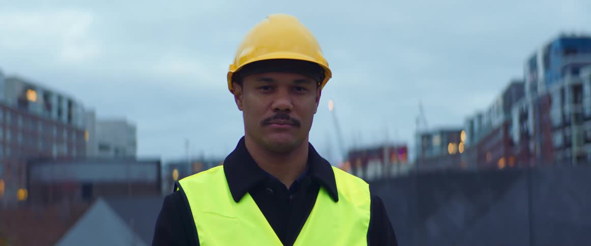 Construction worker wearing a vest and yellow helmet in a residential neighborhood