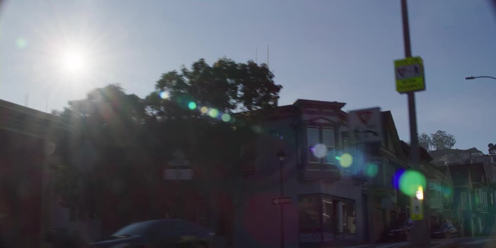 The sutro tower on a hill is visible from neighborhood streets on a bright day