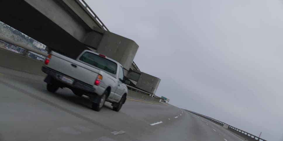 Traveling on a highway around a bend and a silver pick up truck passes ahead