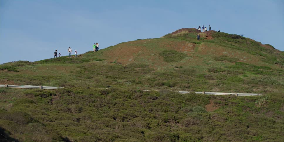 A group of people descending hill seen from a moving vehicle on sunny day