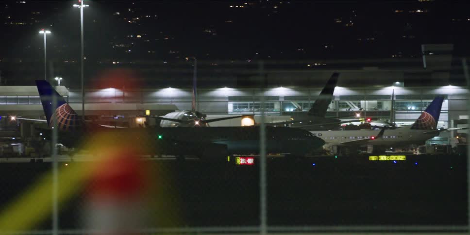 Driving next to the airport where an airplane is taxiing in the runway at night