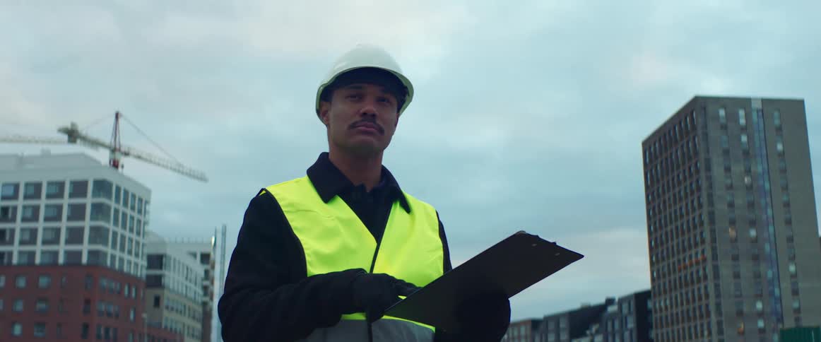 A construction worker holds a clipboard on a construction site