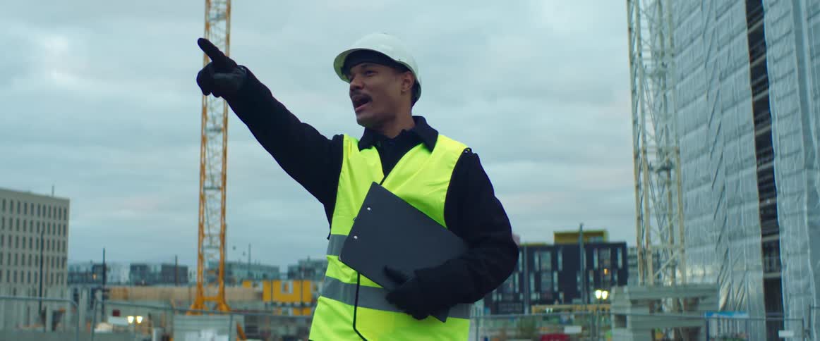 Male project manager at construction site pointing and talking