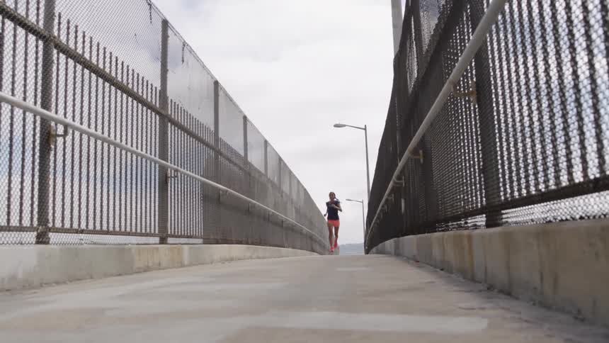 Woman jogging across a bridge with high fences on both sides