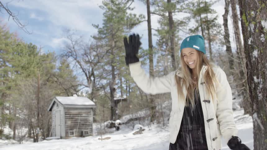 A woman smiles as she swats a snowball thrown at her