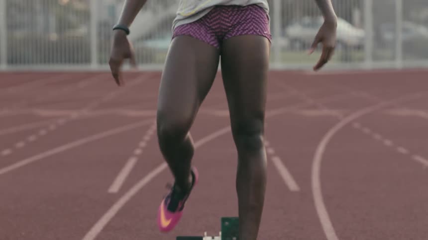 A runner setting her feet in starting blocks and preparing to sprint