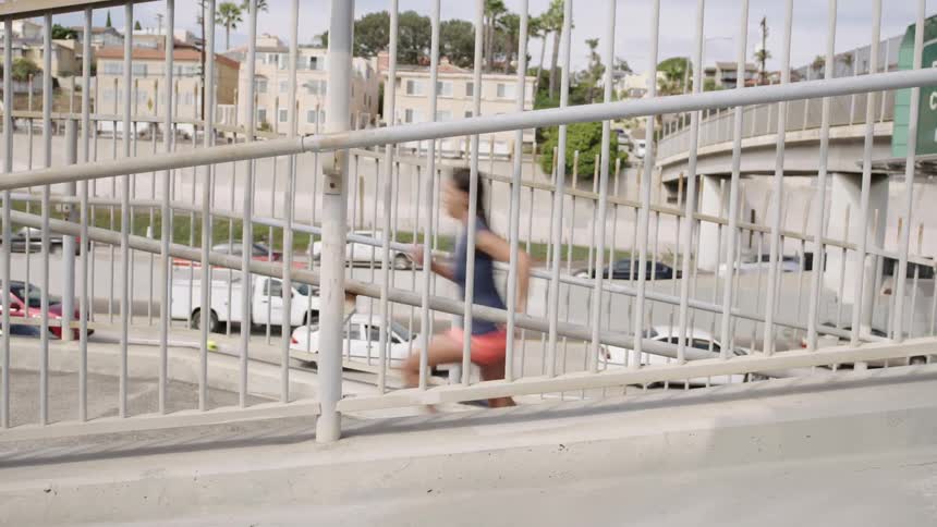 A woman runs up a stairwell in a railing over a road