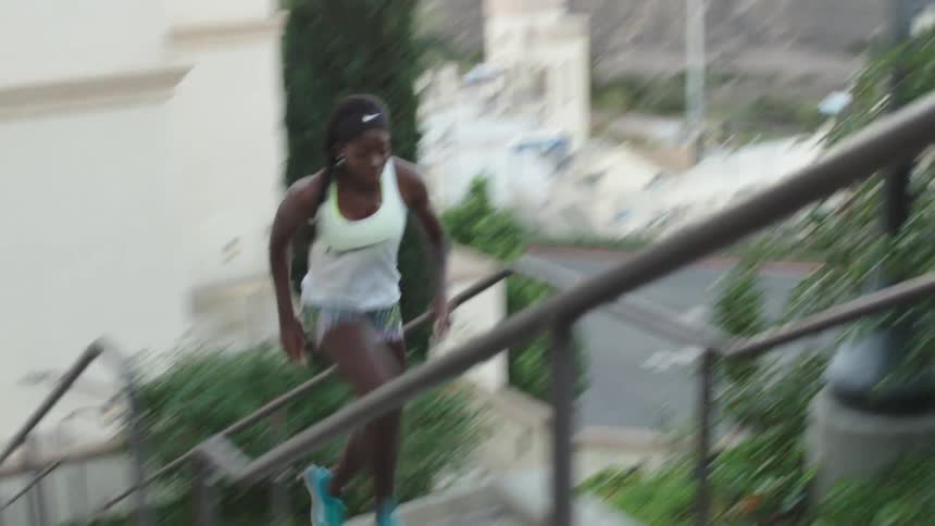 A woman sprinting up a flight of outdoors stairs