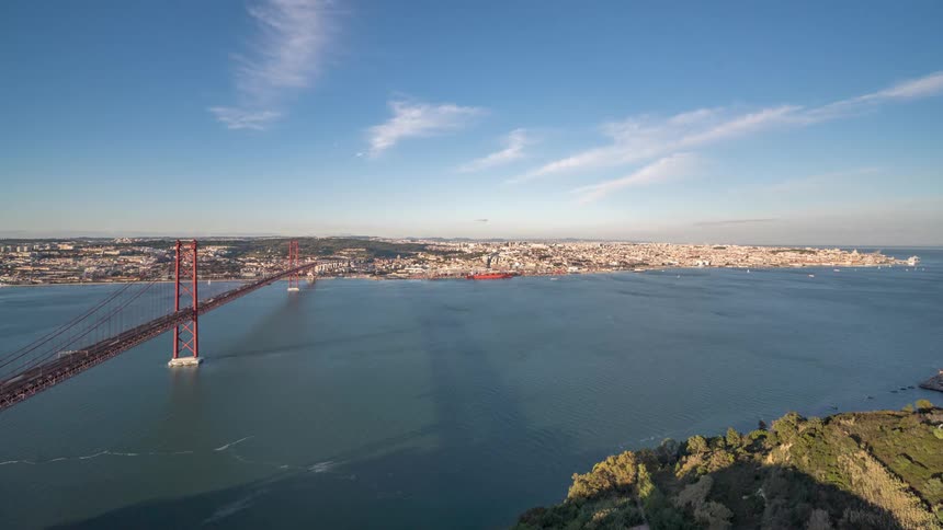 Distant view of suspension bridge over river and city buildings