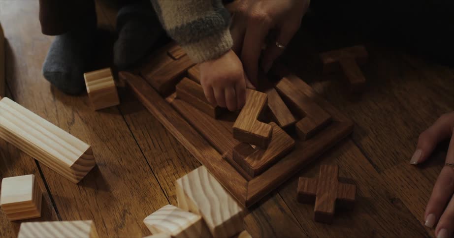 Mother and son playing with a wooden puzzle on the living room floor