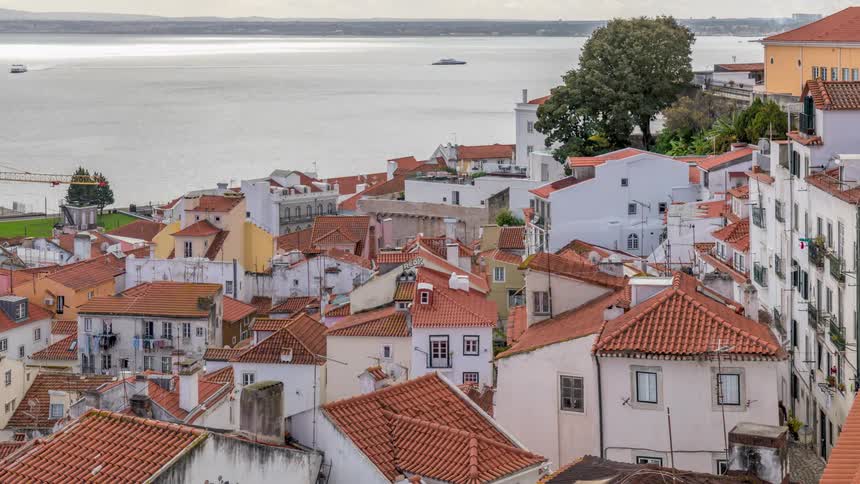 Time lapse of boats sailing in front of a small waterfront town with red tiled roofs