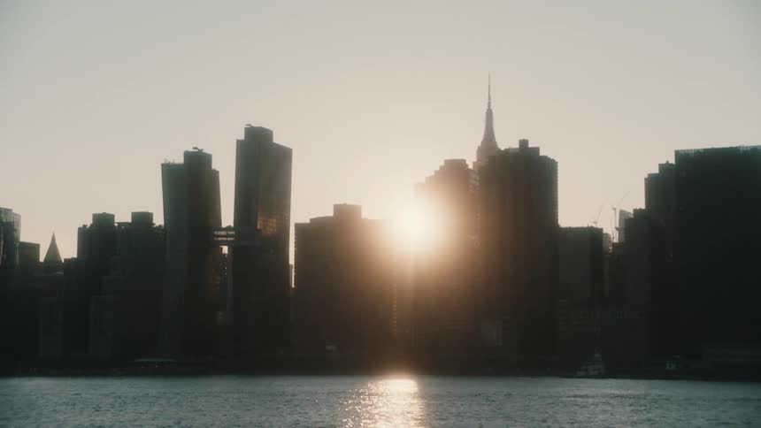 View of a big citys skyline and a river with a boat sailing by