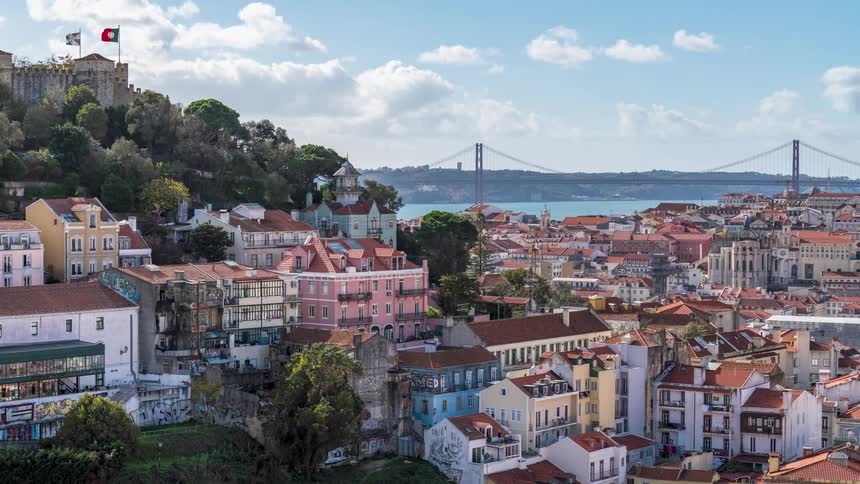 Flags wave in the wind on the castle on a hill overlooking lisbon and the bridge