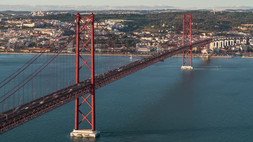 Boats sail underneath the golden gate bridge as traffic moves across