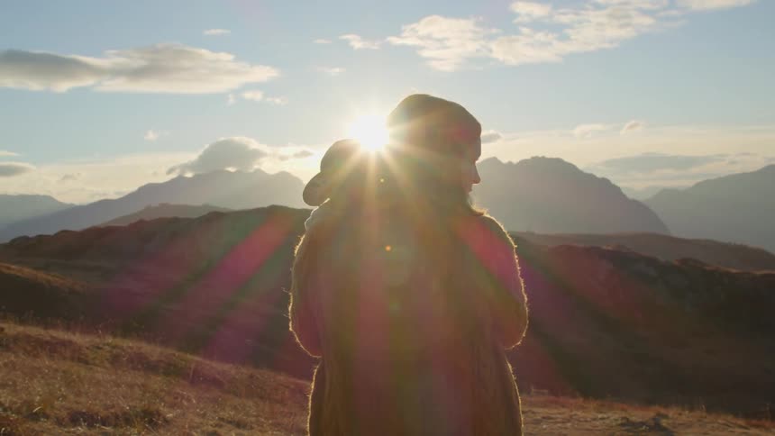 Mother stading outdoors holding her baby while looking to the landscape