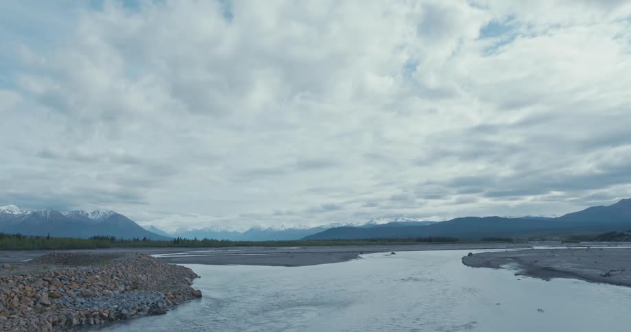 River flowing on a barren landscape near the mountains on an overcast day