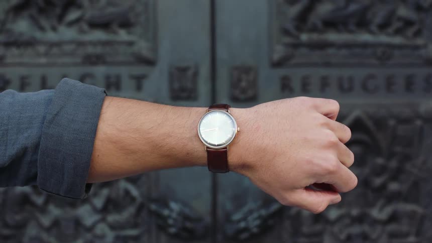 Arm of a man wearing long sleeve shirt and a wristwatch