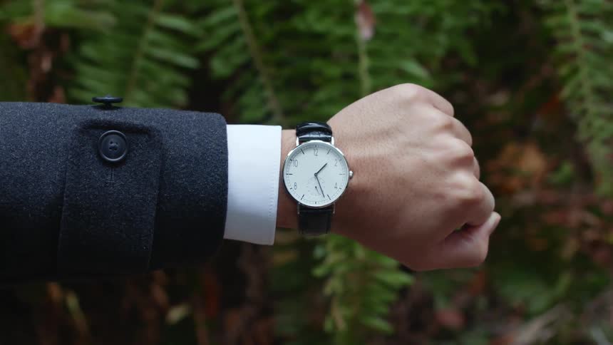 Arm of a man wearing a wristwatch and a suit and white shirt