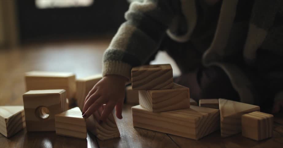 A child plays with wooden building blocks on the floor