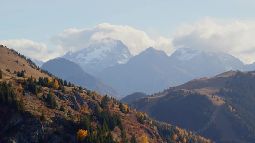 Landscape of big mountains covered in snow and hills full of plants on the horizon