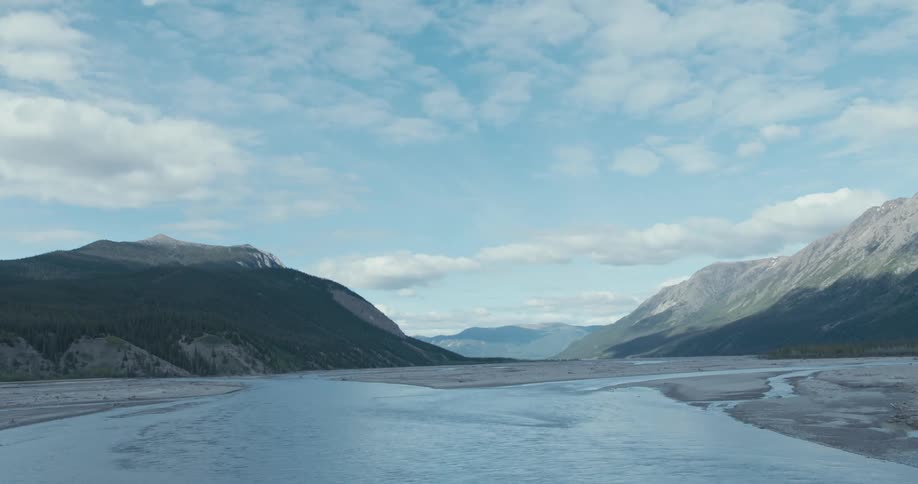 Water flows toward beach with mist covered mountains on horizonunder a cloudy sky