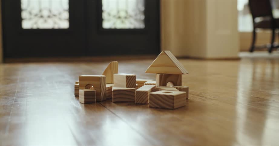 Wooden toy building blocks are sitting on a hardwood floor
