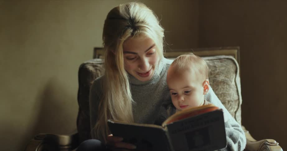 A young woman reads to her infant son at home