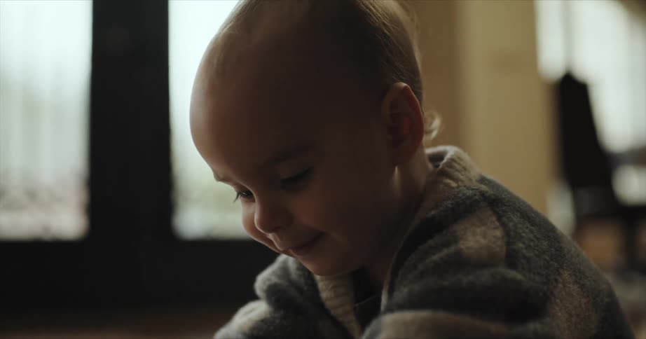 Happy baby wearing a thick sweater playing in the floor of the living room