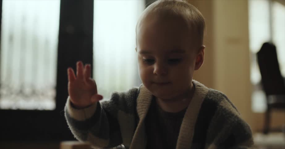 Toddler looks around after wooden tower he is building falls