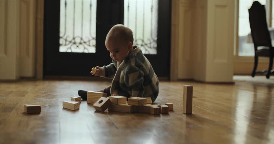 A baby crawls on the floor while playing with wooden blocks