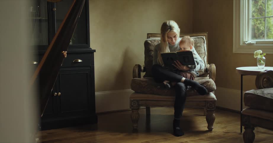 Mother reads to toddler sitting in her lap