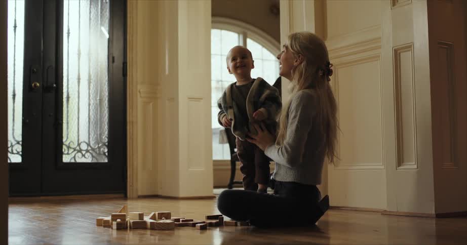 Mother sitting at the floor inside the house playing and laughing with her sondaughter