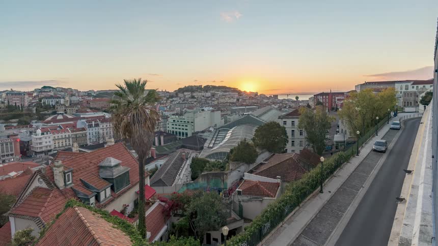 Time lapse of sun rising over the red tiled roofs on he houses and buildings of a small coastal town