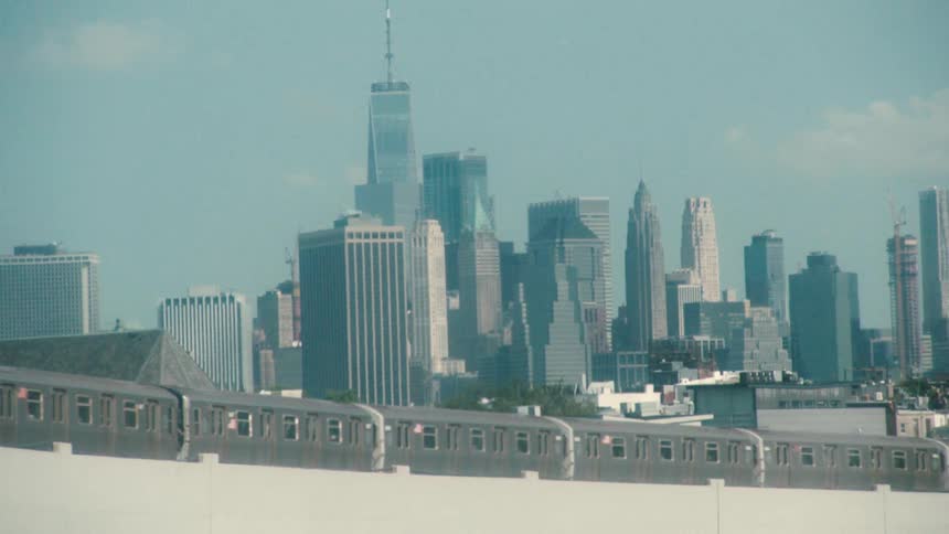 Passenger train traveling in front of the new york city skyline at daytime