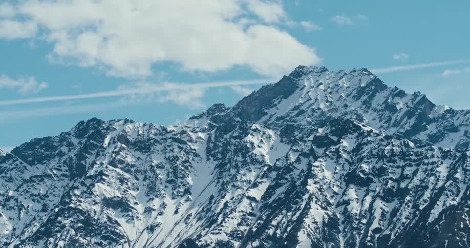 Snow covered mountain high in a cloudy sky